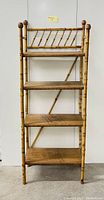 Front view of bamboo shelving unit, showing all four shelves and bamboo frame with diagonal decorative top section.
