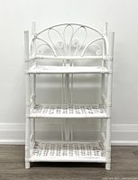 Front view of white bamboo 3-shelf unit with woven shelves and decorative back.