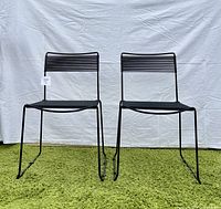 Front view of two black chairs on green rug against white backdrop