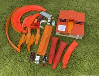 Wide shot showing all parts of the Hot Wheels Two Way Super Charger lot including building, track pieces, and cars on green carpet.