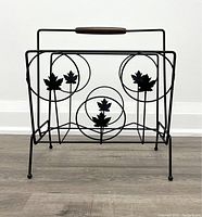 Front view showing metal frame with circular leaf motifs and walnut handle on top.