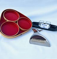 Vintage MCM bentwood red lacquer tray set with three round compartments, chrome and teak crumb sweeper set, small black catch-all tray, two Scandinavian glass candlesticks on black tray.