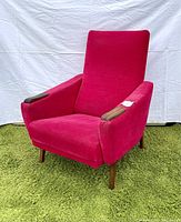 Front and side view of hot pink high back armchair on green shag carpet with teak armrests and legs.