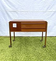 Front view of teak sewing table on wheels