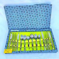 Full view of the cutlery set inside the blue floral patterned box with yellow interior holding the cutlery pieces neatly arranged in rows.