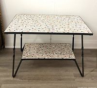 Full frontal view of the vintage metal frame table with mosaic tile surfaces on top and lower shelf, showing overall design and condition.