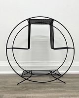 Front view of the black round metal plant stand showing the round frame and three-tier construction.