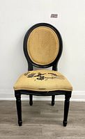 Front view of upholstered accent chair with oval backrest and black frame