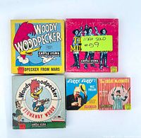 Photo of 5 vintage home projector movie film packages by Castle Films including Woody Woodpecker titles and vintage comedy films. Packaging shows wear.