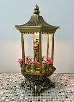 Front view of entire lamp showing pagoda roof, columns, goddess figurine, strings and flowers
