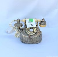 Front view of vintage ornate metal rotary dial telephone showing handset, rotary dial, hardwire cord, and base with decorative metal detail.