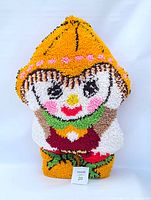 Front view of the vintage rug hooked Dutch Boy pillow showing the character's face and upper body with vibrant colors and textured hooked yarn.