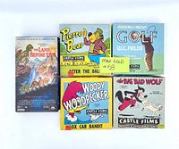 Lot of 4 vintage 8mm projector films and 1 VHS movie showing front of boxes and cover art.
