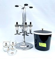 Front view of the vintage 4-bottle liquor dispenser, black and white insulated ice bucket with star detail on lid, four small bowling motif glasses, and matching ashtray on white background.