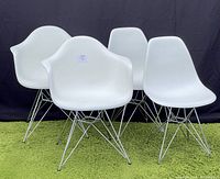 Front view of all four chairs: two armchairs in front, two side chairs behind on green turf and black backdrop