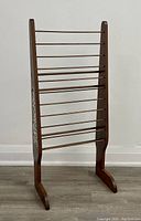 Front view of tall wooden magazine or shawl holder showing dowel rungs and wooden frame.