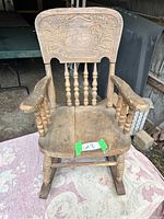 Front view of antique child's rocking chair showing carved press back and spindle supports