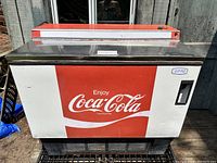 Front view of vintage Coca-Cola cooler chest showing red and white graphics with 'Enjoy Coca-Cola' logo.