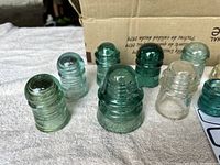 Close-up image of seven teal/blue and clear glass insulators showing details of color and glass texture.