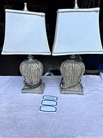Two matching table lamps with rectangular white/cream fabric shades and ceramic crackle finish bases on a table.