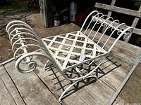Side angle showing white metal outdoor seat frame with lattice seat and curved armrests