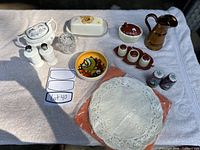 Full view of all the miscellaneous china and decorative pieces laid on a white towel, showcasing the variety in the lot