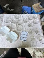 Overview of all clear pressed glass nappies and two white milk glass dishes on a table