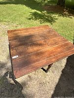 Top view of rustic pine drop leaf table in outdoor setting illustrating natural wood grain and wear marks on surface.