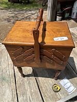 Cherry wood sewing basket box closed, showing the top, handle, and legs