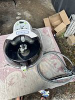 T-fal air fryer with digital controls and transparent lid on table, alongside shower head hose.
