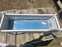 Top view showing the rectangular white wicker stand with blue interior base and a label with a lot number.