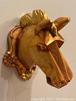 Close-up side view of the gold geometric horse head wall decor showing details of the swirl etching and sculpted ears and mane.