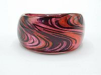 Side angle showing black swirl over pink and orange glitter pattern lucite bangle bracelet.