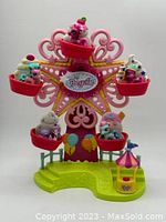 Front view of pink and green Ponyville Ferris Wheel toy with 5 mini ponies in red bucket seats.