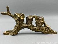 Front and side view of the entire brass owl sculpture on a branch showing three stylized owls with detailed eyes and feathers.