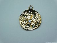 Front view of circular 10K gold sand dollar pendant with textured finish, star design, and central diamond.