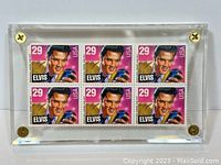 Six 29 cent Elvis Presley stamps mounted in clear acrylic block with brass screws displayed flat showing all stamps.