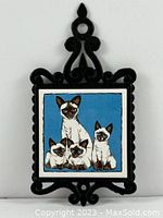 Full front view of the black cast iron scroll frame with ceramic tile showing five Siamese cats on blue background.
