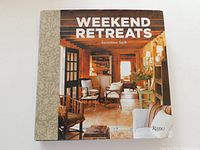 Front cover of Weekend Retreats hardcover coffee table book by Susanna Salk featuring a cozy rustic interior design photo and patterned spine.