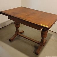Full view of the rectangular antique wooden kitchen table with two pedestal legs and end leaves tucked in.