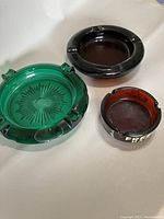 Three vintage glass ashtrays in photo showing full set and details