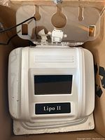 Main Lipo II unit inside cardboard box showing white plastic housing, display screen and model label