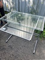 Front angle view of glass desk showing slide-out keyboard tray and metal frame.