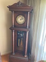 Full view of the solid wood grandfather clock with carved details, showing the entire height and structure.