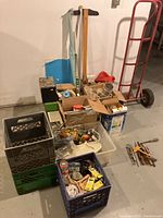 Lot overview showing milk crates, hand truck, boxes of miscellaneous items including hardware and tools