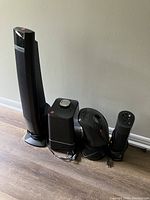 Four small black appliances consisting of three electric heaters of varied designs and one small humidifier or similar device.