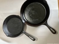 Two cast iron frying pans placed on white background, showing top side with handles
