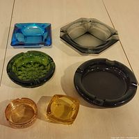 All five colored glass ashtrays displayed from top view showing various shapes and colors