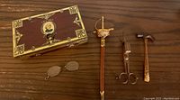Photo showing the cigar case, small sword with cover, small hammer and scissors, and small spectacles.