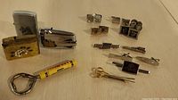 Full view showing three vintage lighters, five pairs of cufflinks, six tie clips, and a yellow and metal bottle opener.